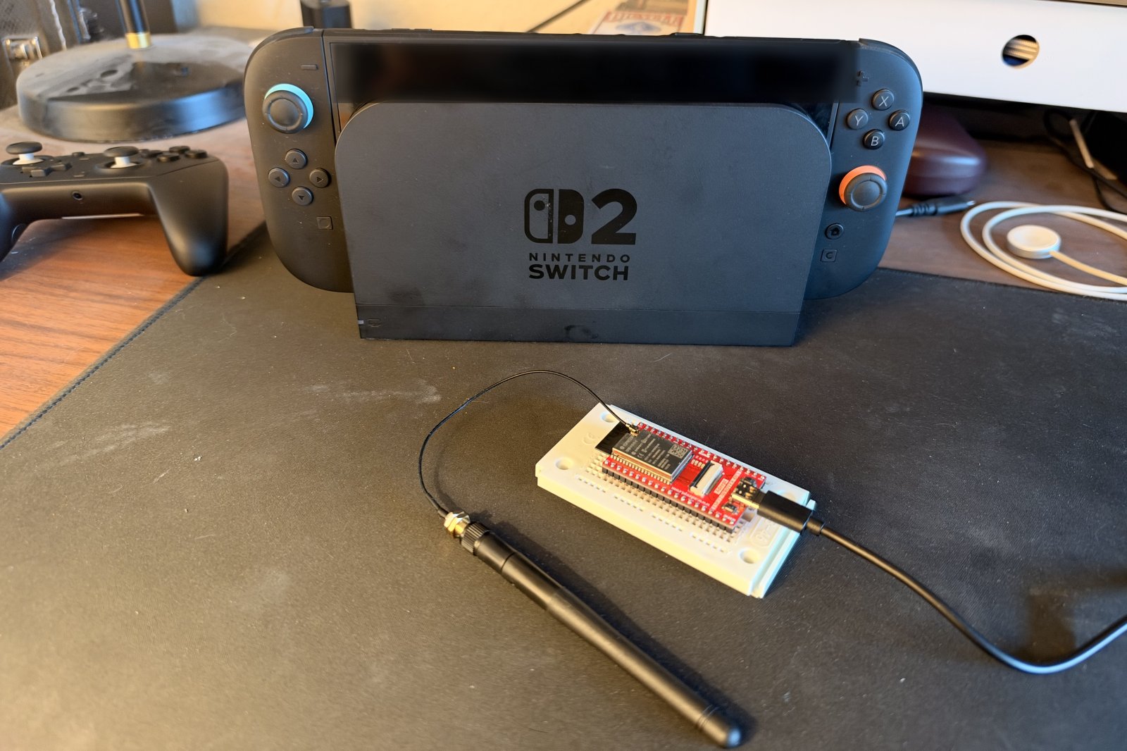 Switch 2 im Dock, davor der ESP32-WROVER auf der Adeept-Platine mit angesteckter Antenne, links der Pro-Controller-Nachbau
